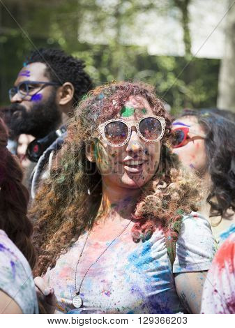 NEW YORK - APR 30 2016: A woman in the crowd with colorful powder on her face celebrating the Holi Hai Festival of Colors hosted by NYC Bhangra in New York on April 30 2016.