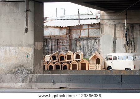 Pile of wooden dog houses near kombi car under bridge