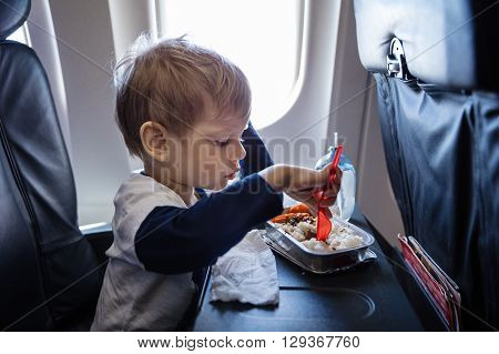 Little boy having a meal on board of a plane