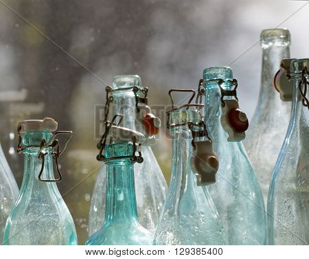 Group of back lit blue and transparent old fashioned empty glass bottles in a window