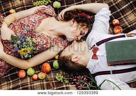 Beautiful Happy Bride And Stylish Retro Groom Lying On Tweed Blanket, Kissing And  Relaxing, Picnic