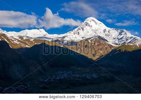 View of Kazbegi mountain and Stepantsminda village at sunrise
