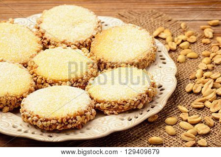 Butter cookies (alfajores) with caramel and peanut on wooden background.