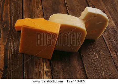 various types of fresh raw aged delicatessen cheese on wooden table cheddar edam swiss