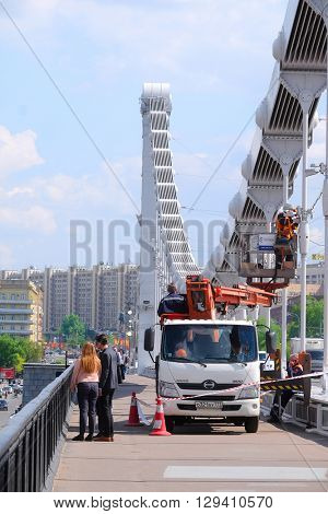 Moscow, Russia - May, 6, 2016: workers on the car lift repair to elektrset on Krymsky Bridge in Moscow, Russia
