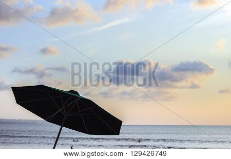 dark shape of parasol on beach during sunset