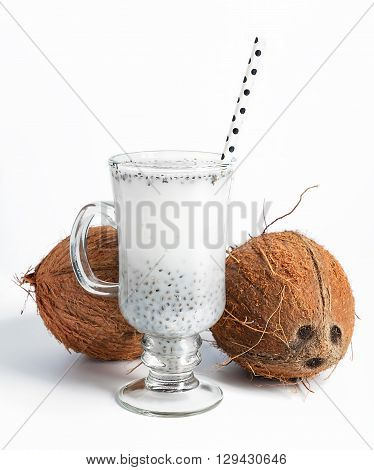 Coconut milk with chia seeds served in glass with white paper polka dot straw. Cold and refreshing drink. On white background. Selective focus.
