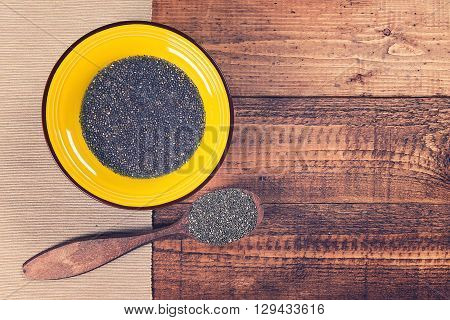Chia jelly in a plate with spoon full of dry chia seeds on grunge wooden background. Toned.