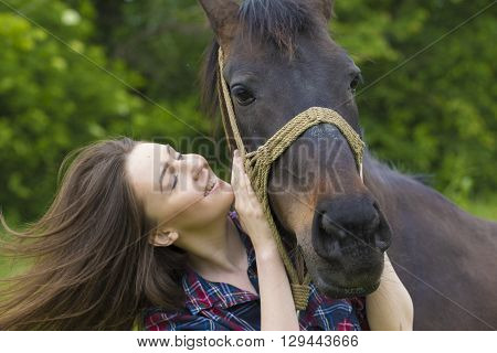 Smiling young girl with long hair love her mare