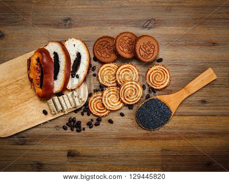 There are Pieces of Roll with Poppyseed,Cookies with Halavah and Chocolate Peas,Tasty Sweet Food on the Wooden Background,Top View
