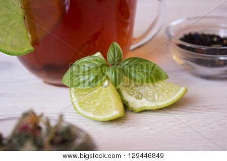 Hot tea in a cup with lime Pieces and basil