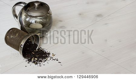 Dry tea and teapot at white wooden background