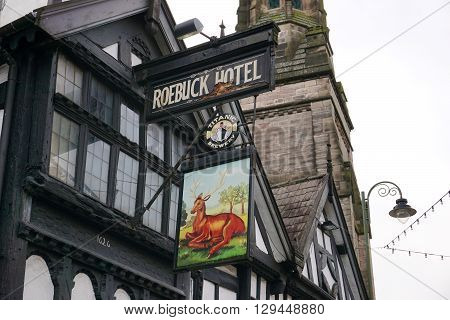 LEEK, UK - DECEMBER 31: A brightly-painted sign for the Roebuck Hotel hangs from a historic wattle and daub building along the high street in Leek, a market town in the Staffordshire Moorlands, England, on December 31, 2015.