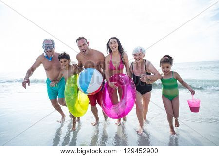 Happy multi-generation family running on sea shore at beach