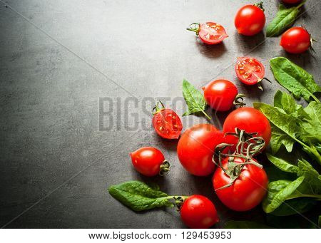 Tomatoes and spinash at slate background with space for text. Healthy eating and Diet concept. Vegan food background.