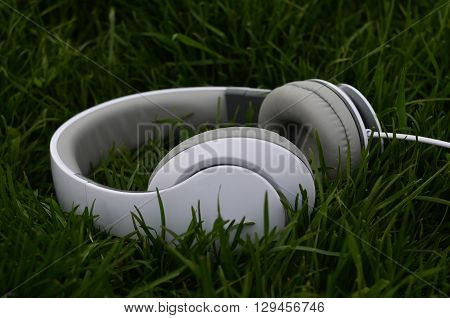White big headphones on green spring grass