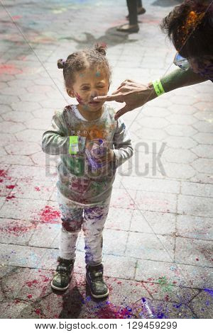 NEW YORK - APR 30 2016: An unidentified girl celebrates Holi Hai Festival of Colors with colorful powder on her face in Dag Hammerskjold Plaza hosted by NYC Bhangra in New York on April 30, 2016.