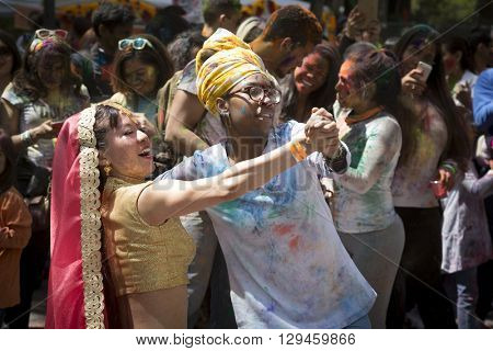 NEW YORK - APR 30 2016: A female member of NYC Bhangra and a spectator dance together in the crowd at the Holi Hai Festival of Colors in Dag Hammerskjold Plaza in New York April 30, 2016.