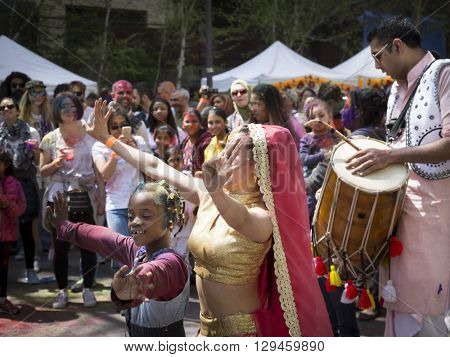 NEW YORK - APR 30 2016: A female member from NYC Bhangra dances with a little girl in the crowd at the Holi Hai Festival of Colors in Dag Hammerskjold Plaza in New York April 30, 2016.