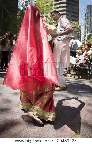 NEW YORK - APR 30 2016: A dancer and drummer from NYC Bhangra perform in traditional clothing in the crowd at the Holi Hai Festival of Colors in Dag Hammerskjold Plaza in New York April 30, 2016.