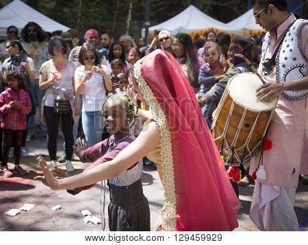 NEW YORK - APR 30 2016: A female member from NYC Bhangra dances with a little girl in the crowd at the Holi Hai Festival of Colors in Dag Hammerskjold Plaza in New York April 30, 2016.