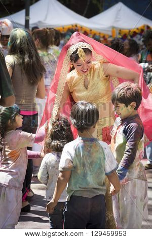 NEW YORK - APR 30 2016: A female member of NYC Bhangra dances with a group of young  children in the crowd at the Holi Hai Festival of Colors in Dag Hammerskjold Plaza in New York April 30, 2016.