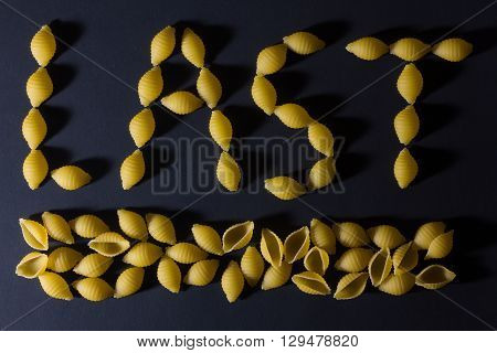 LAST word pasta laid out in the form of seashells on a dark background .