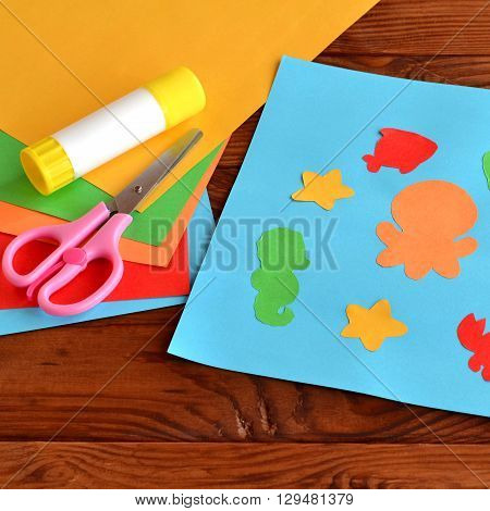 Paper applique with sea animals and fishes. Art lesson in kindergarten. Paper sea animals - octopus, fish, starfish, seahorse, crab. Kids diy. Sheets of colored paper, scissors, glue