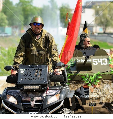 Orel Russia - May 9 2016: Celebration of 71th anniversary of the Victory Day (WWII). Men in uniform driving military machines with red flags closeup