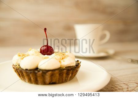 Cake with a cherry and white cup on the table