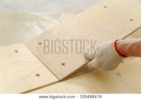Laying plywood on the floor. The worker put a piece of plywood on the floor with glue.