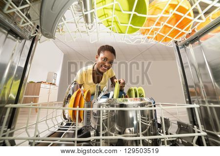 Young Happy African Woman Removing Plate From The Dishwasher