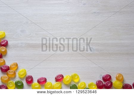 Colorful candy decoration frame over wooden white background