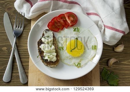 Breakfast: Fried egg in form of a clock, tomato and sandwich with fork and knife