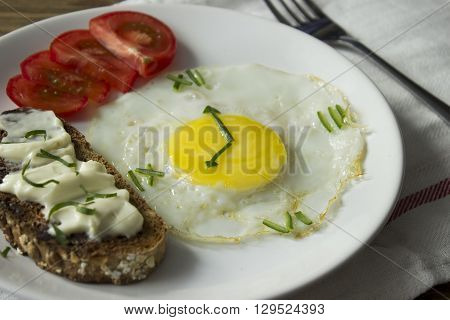 Breakfast: Fried egg in form of a clock, tomato and sandwich with fork