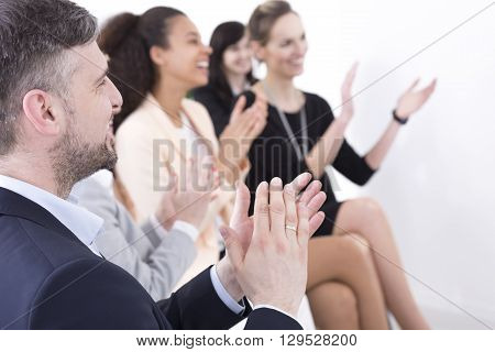 Shot of a team of businesspeople clapping hands while having a meeting