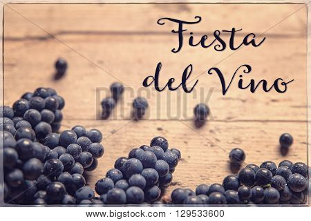 blue grapes on wooden table spanish text fiesta del vino which means wine festival vintage filtered