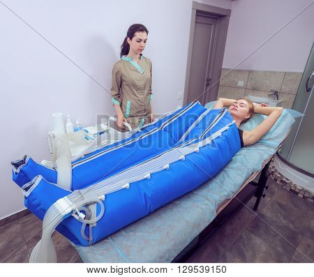 Body pressotherapy machine on woman in beauty center. Beauty girl makes a correction figure and lose weight in pressotherapy. Figure correction and massage in the beauty clinic. Pressotherapy machine