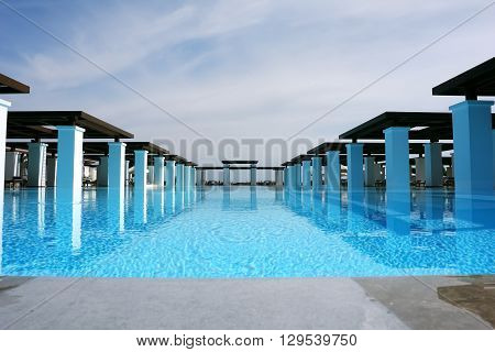 HERAKLION, CRETE, GREECE - MAY 13, 2014: The big blue swimming-pool modern building with columns and beach in popular luxury class hotel on the Mediterranean coast of Crete, May 13, 2014, Greece.