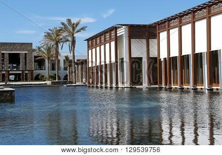 HERAKLION, CRETE, GREECE - MAY 13, 2014: The big blue swimming-pool modern building with columns palms in popular luxury class hotel on the Mediterranean coast of Crete, May 13, 2014, Greece.