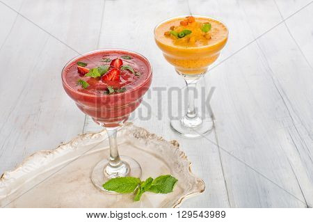 Two glass of strawberry and buckthorn smoothie on a whight wooden background