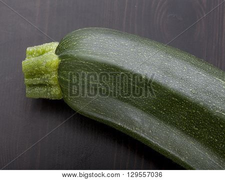Top view of green zucchini piece on the black wooden table