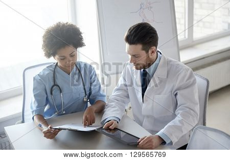 health care, people, technology and medicine concept - doctor and nurse with tablet pc computer and clipboard meeting and discussing something at hospital