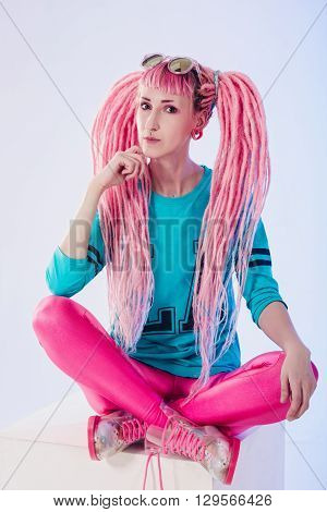 Modern teenage girl with pink dreadlocks on white background