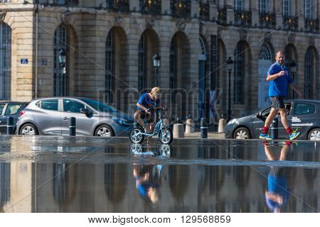 Children Having Fun In A Mirror Fountain In Bordeaux