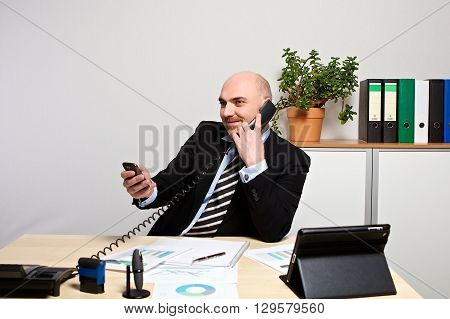 Manager On The Phone While He Checks His Smartphone