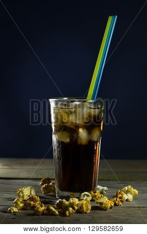 Glass of cola with ice on old wooden table