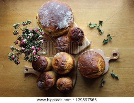 Homemade Easter bread loafs set background. Homemade sweet bread loafs upper view. Bread loafs on the table with dry roses bouquet.