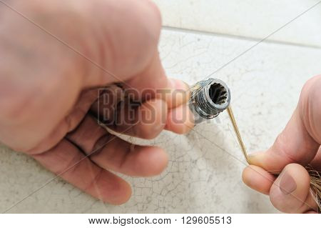 Plumber putting hemp fibers on a thread pipe.