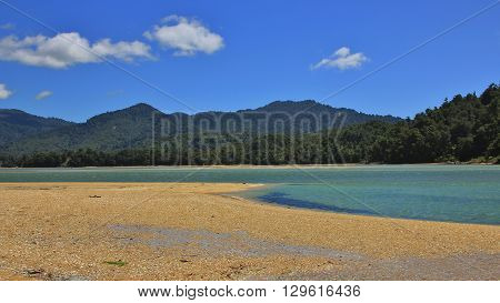 Landscape in the Abel Tasman national park. Awaroa Inlet. Sandy beach blue water and green hills.